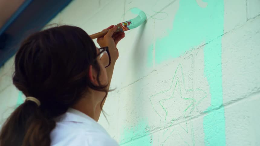 A woman is painting a wall outdoors