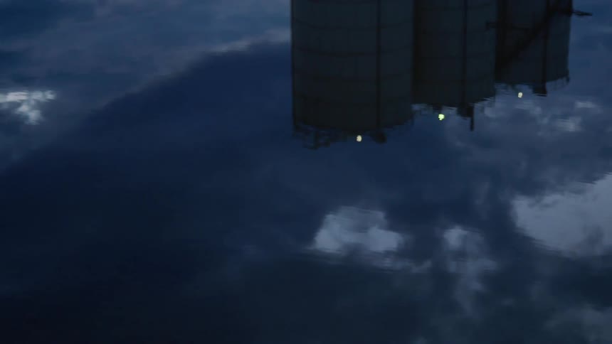 A reflection of silos and lights the sky and clouds in water