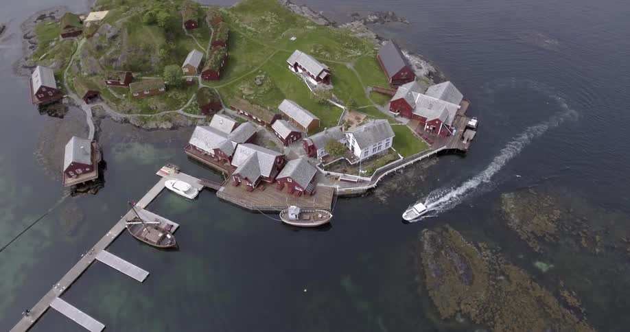 A boat traveling around the tip of an island as it heads towards a pier