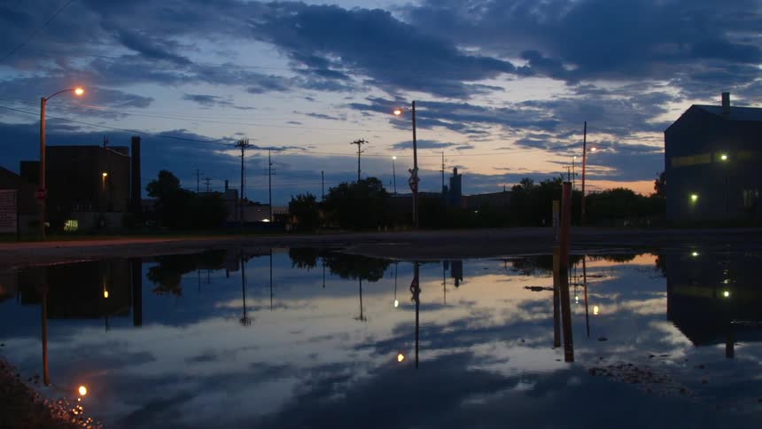 The sky reflects off the water in a city at dusk