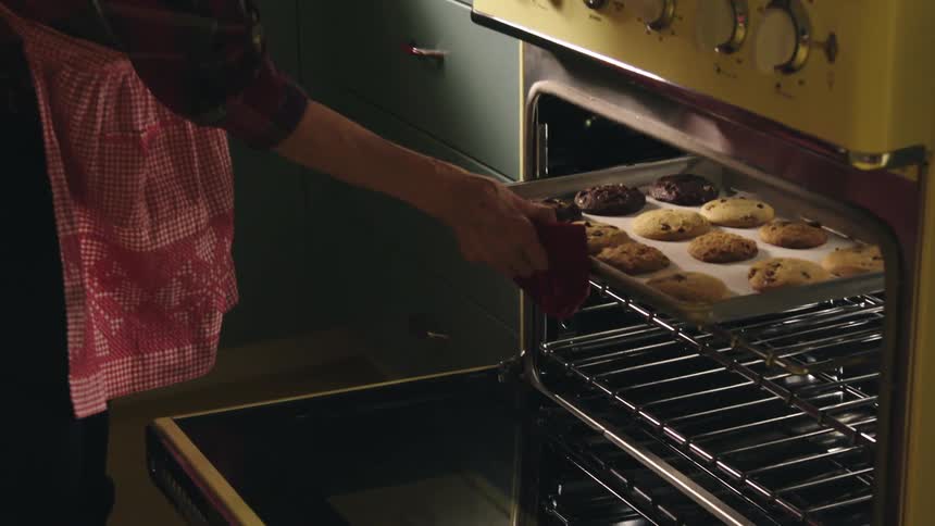 Woman opens oven to check baking cookies for doneness