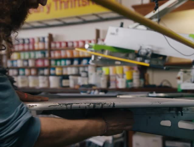 An employee smooths out a t shirt on a piece of machinery
