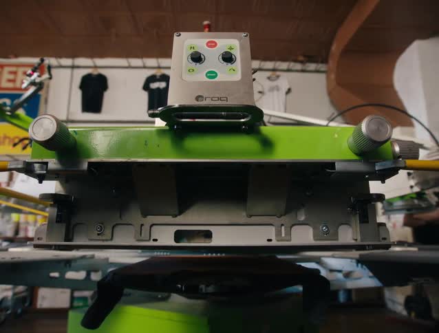 A person with a hat working with a t shirt printing machine