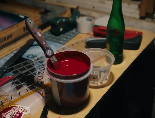 A can of paint on a table with a scissors and a bottle