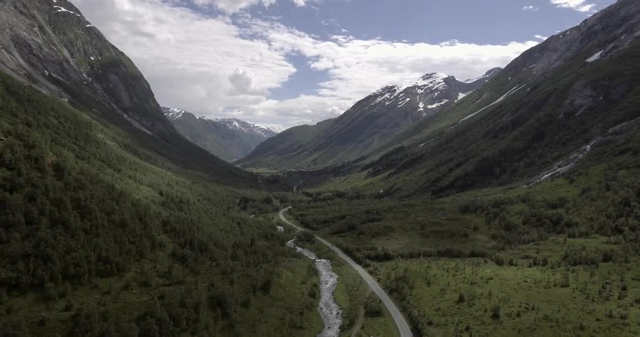 A two lane road and a river running through a mountain valley