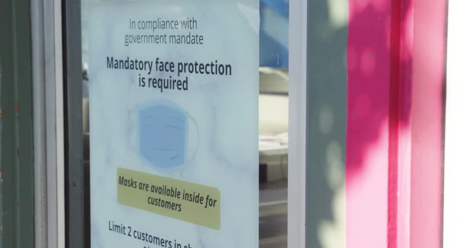 A sign on the front door of a small business states that face masks are mandatory to enter
