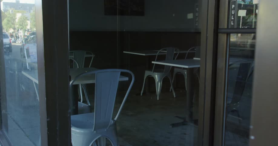 A store window of a restaurant with tables and chairs