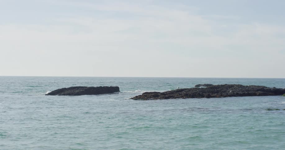 A rocky shore jutting out of the water with the sky and clouds in the background