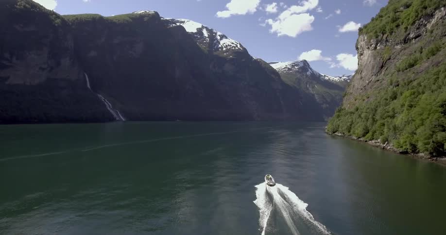 A boat travelling along a river that is surrounded by steep cliffs