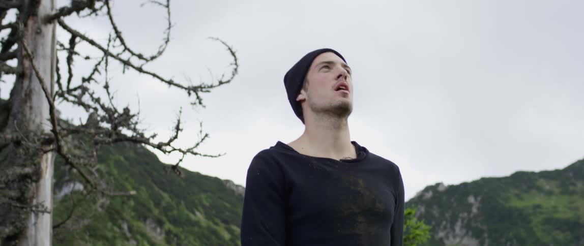 A man is jogging up a hill in the woods