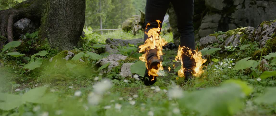 A man with his pants on fire runs through a forest