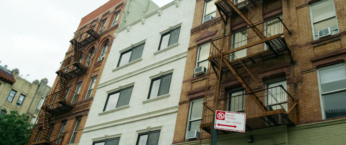 A city with buildings with fire escapes with the sky and clouds above