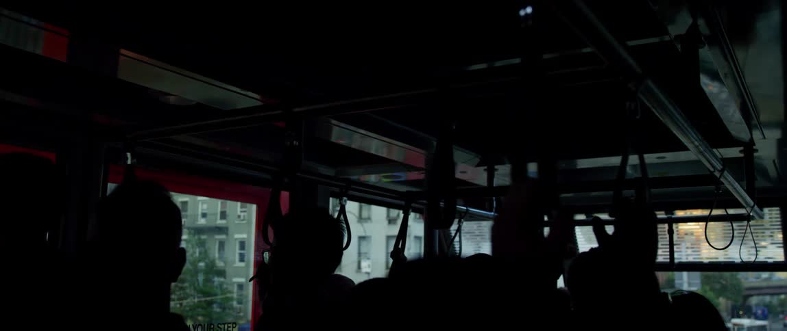 Passengers wait in a dimly lit tram in a metropolis during the day