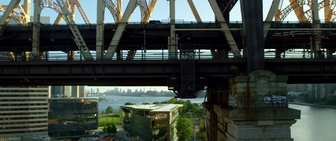 Traffic and pedestrians cross a bridge over a water in a city on a sunny day