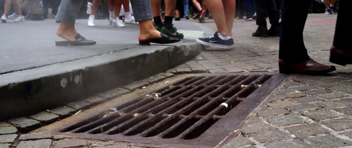 People walking on a city street near a sewer grate