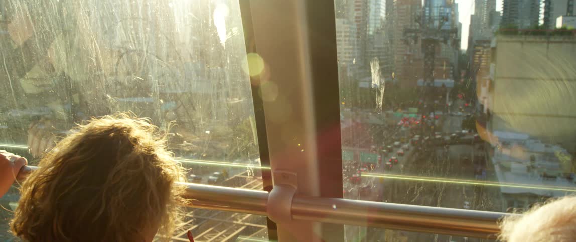 People standing in a tram look down on a busy city street