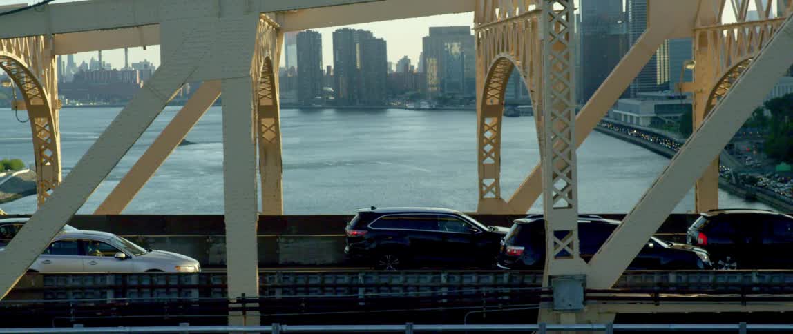 Aerial view of a traffic jam on a bridge over a river in front of the city skyline at sunset