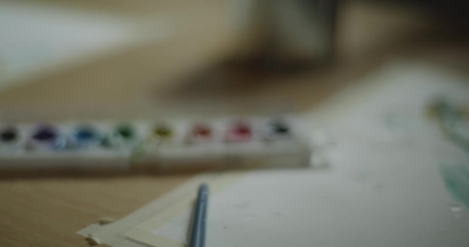 A child painting with watercolors at a wood table