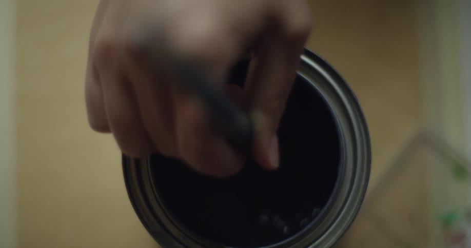 A person is stirring the paint can