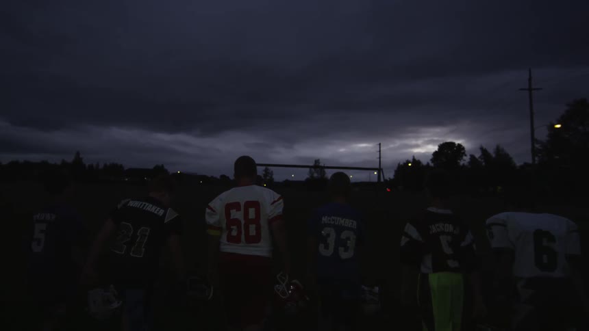 Boys in football gear walking after sunset