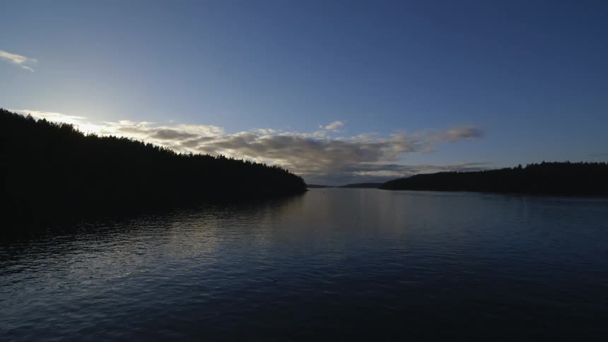 A body of water running between two pine tree lined coasts