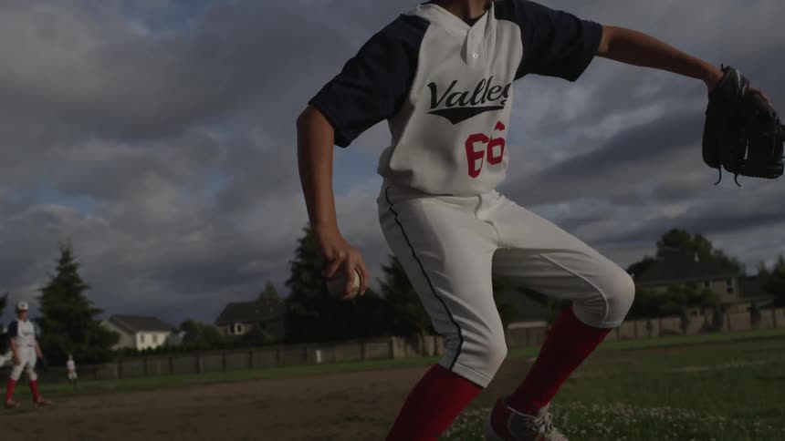 Boy picks up a rolling baseball in his glove and then throws it