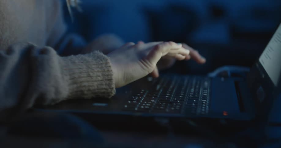 Blonde woman types on keyboard being held in her lap