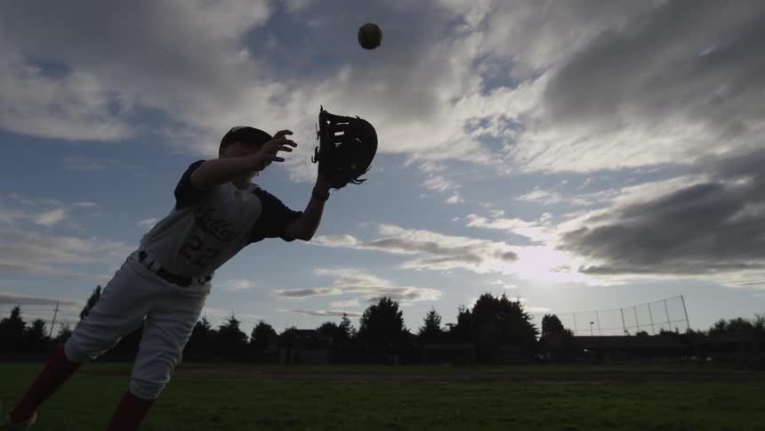 A boy runs and leaps to catch a baseball