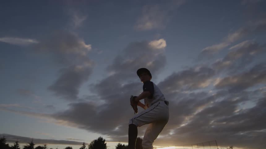 A kid pitches near sunset