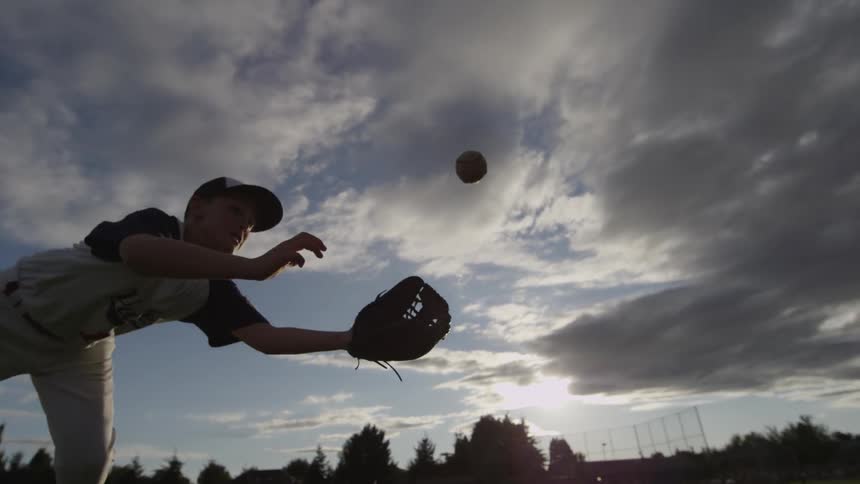 A boy dives to catch a baseball