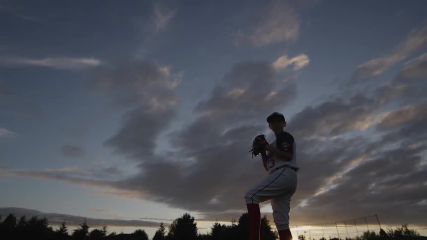 A boy winding up and pitching a baseball
