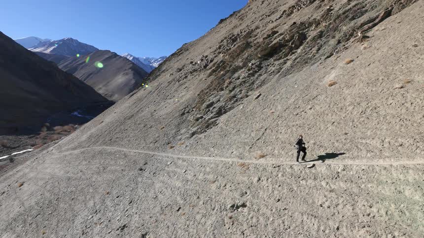 Hiker walking on the side of a bare mountainside