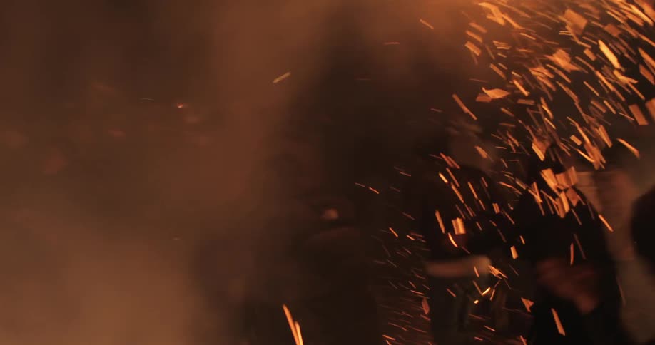 People running through sparks and smoke as they flee a fire