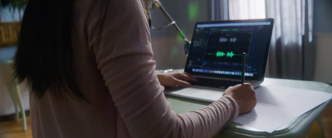 A young musician at home sits in front of her computer and makes notes