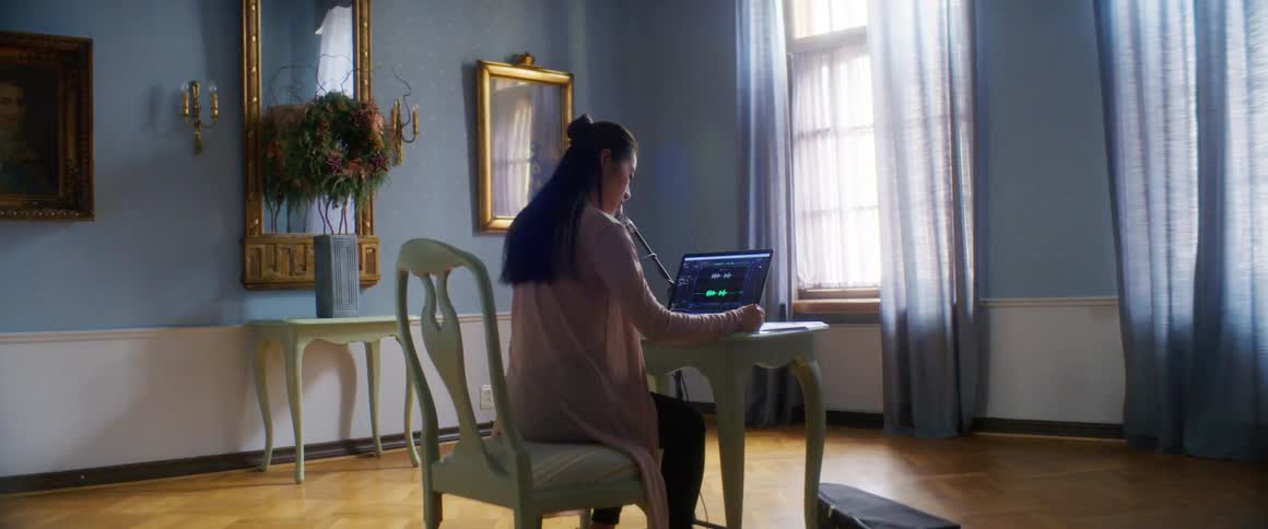A woman sits at home and looks at her laptop