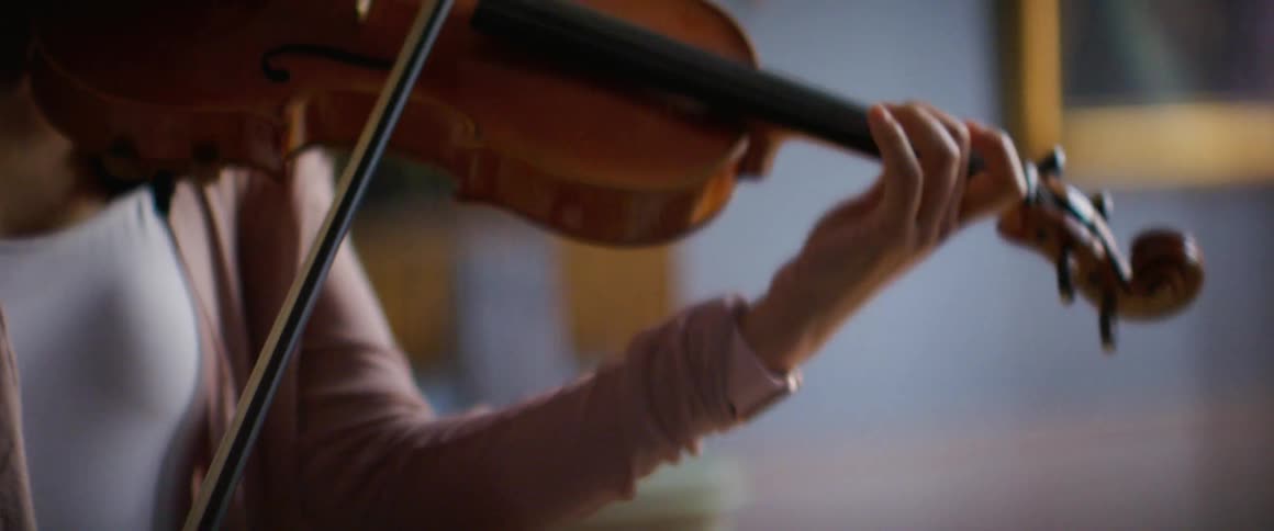 Asian female violinist plays a violin in a large room with paintings