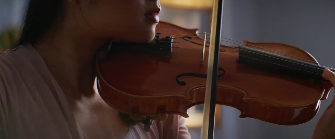 A woman is playing the violin indoors during the day