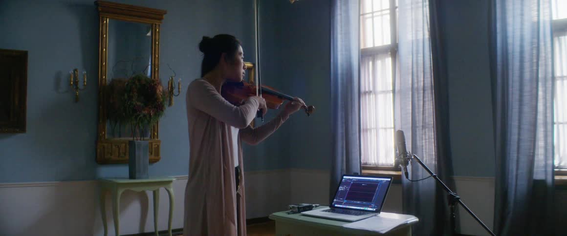 Woman playing and recording viola with a microphone