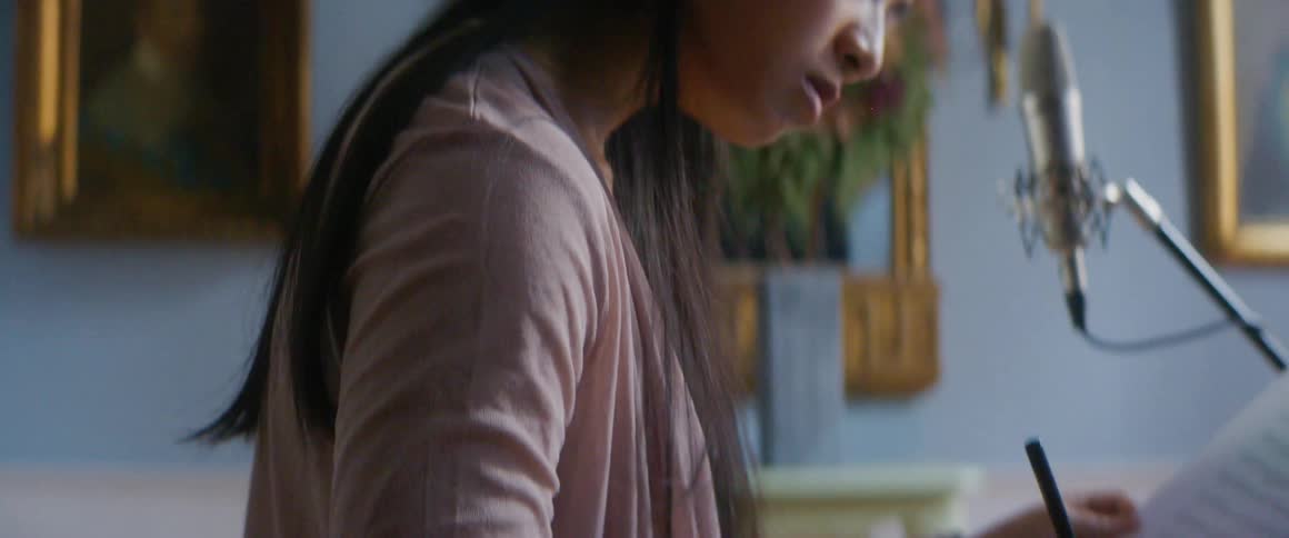 A young woman at home writes music at her laptop
