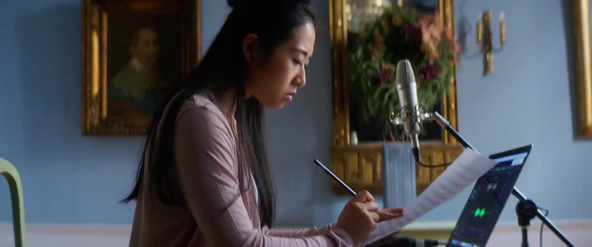 A young woman sits at a desk and writes music