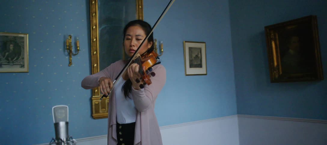 A young woman playing the violin at home