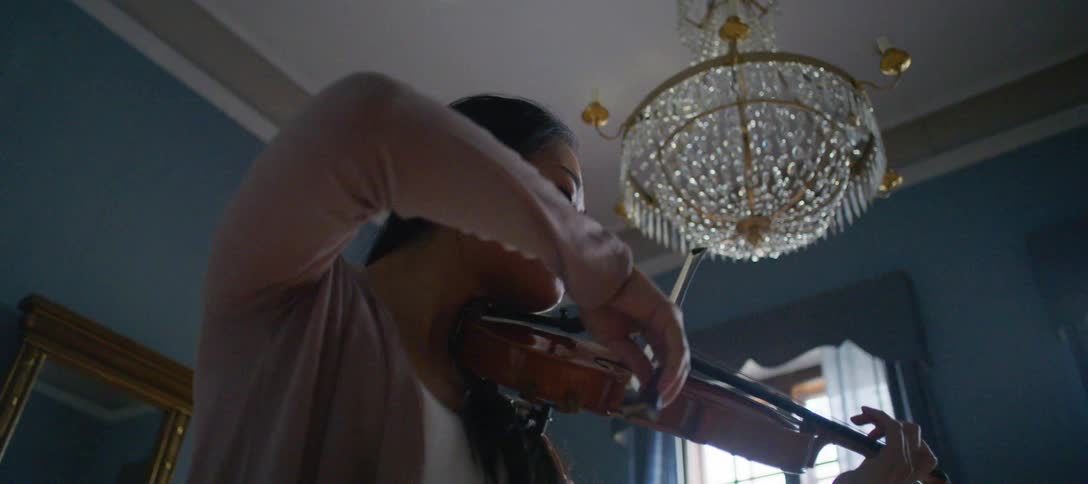 A woman is playing the violin indoors