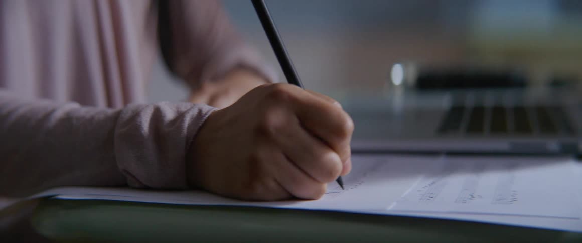 A person sits in front of a laptop and writes music