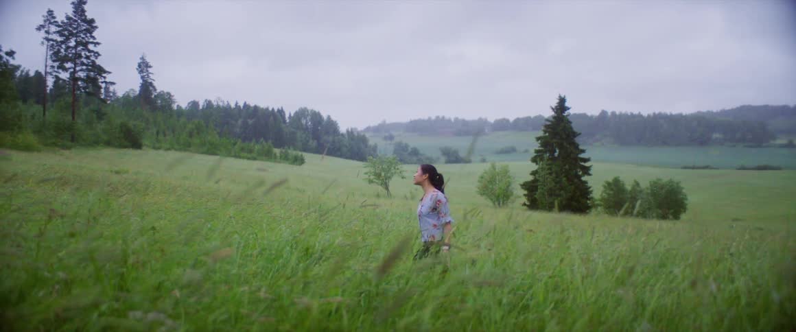 A young woman walks through a grassy field