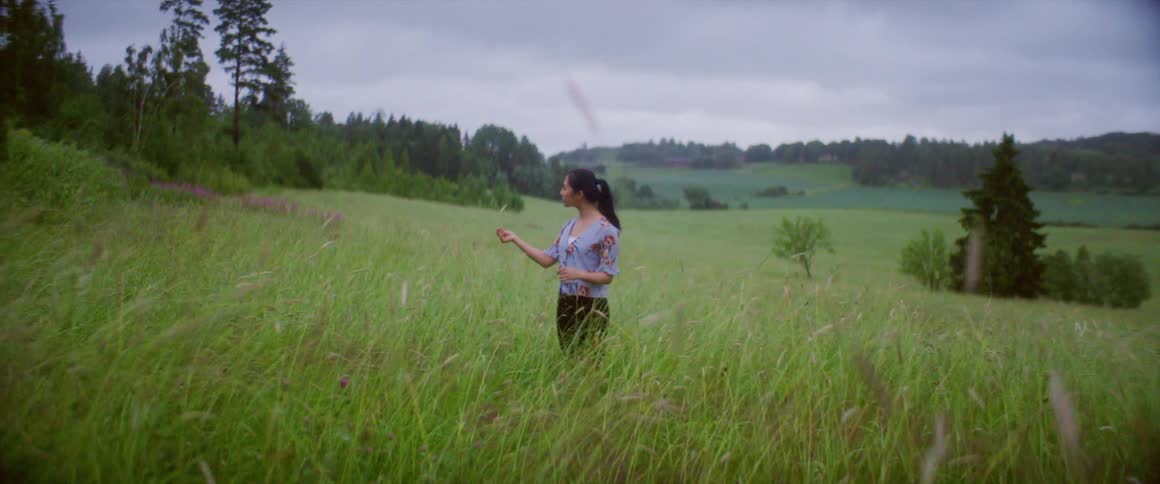 A woman is standing in the tall grass