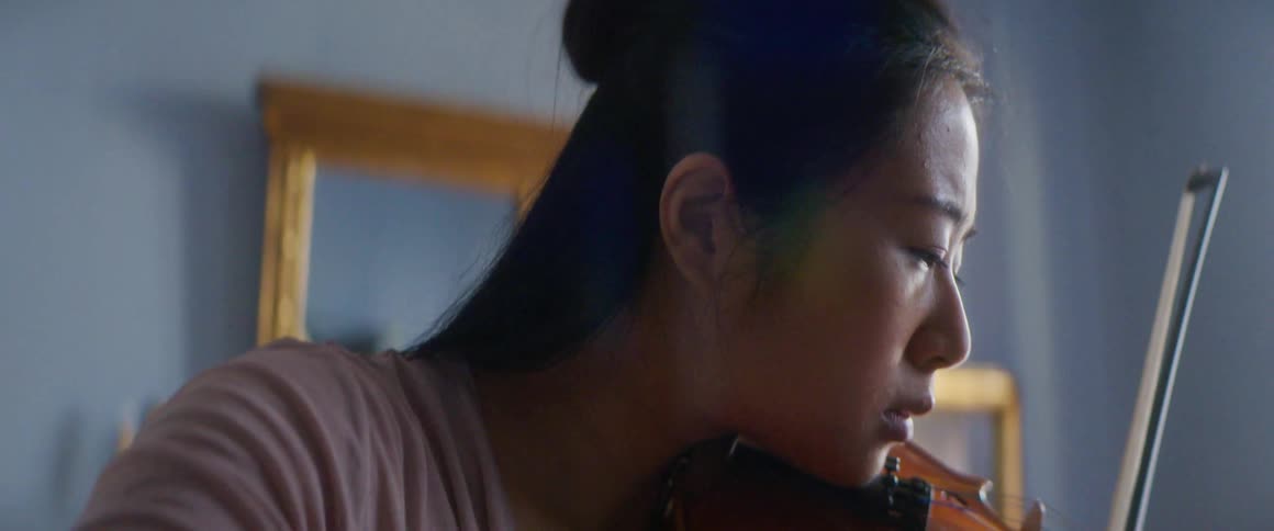 Woman plays string instrument near wall mirror