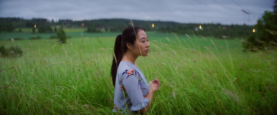 A woman is standing in a grassland area