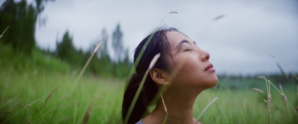 A woman is standing outdoors in the grass