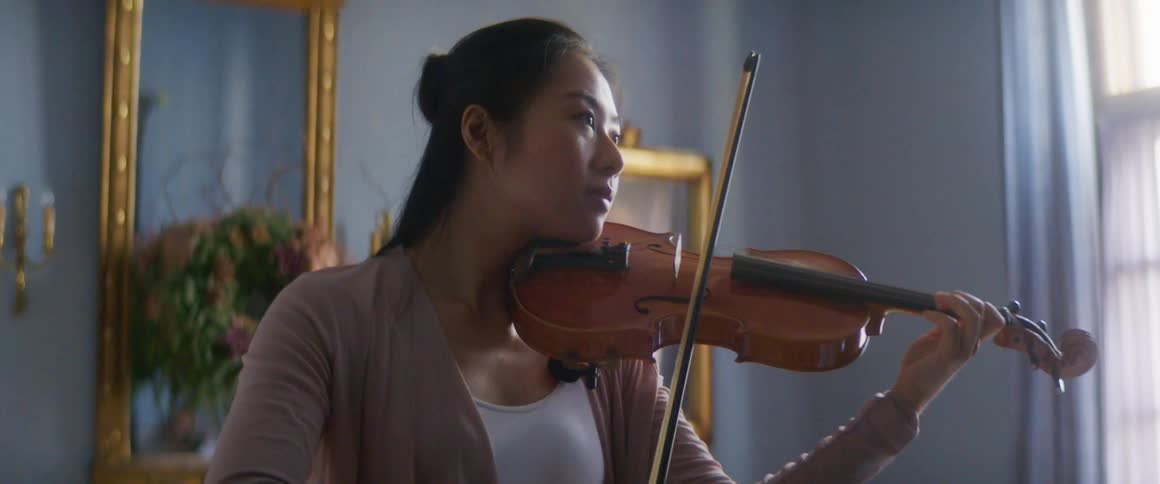 A woman is playing the violin indoors
