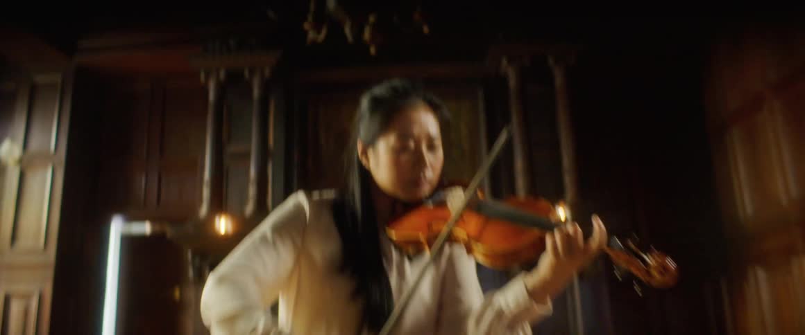 A woman is playing a violin indoors during the day